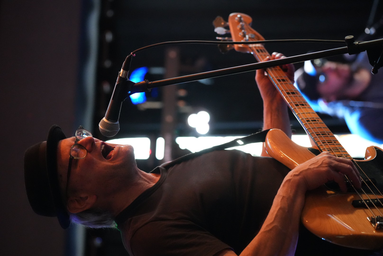 Bass player bending back at the mic